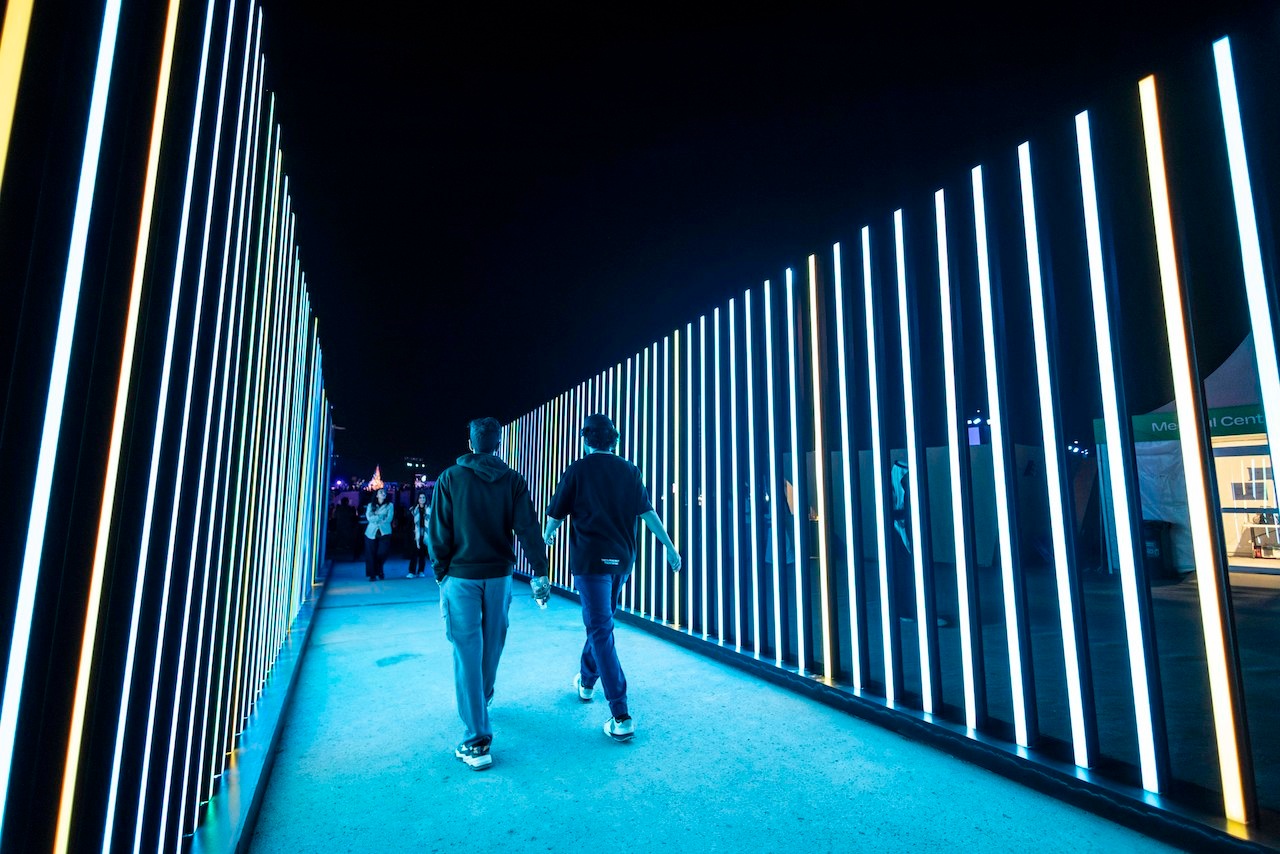 Two men walking through blue LED walkway