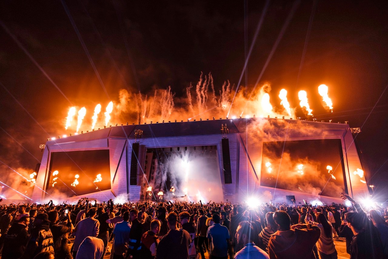 Stage with yellow pyrotechnics in front of large crowd