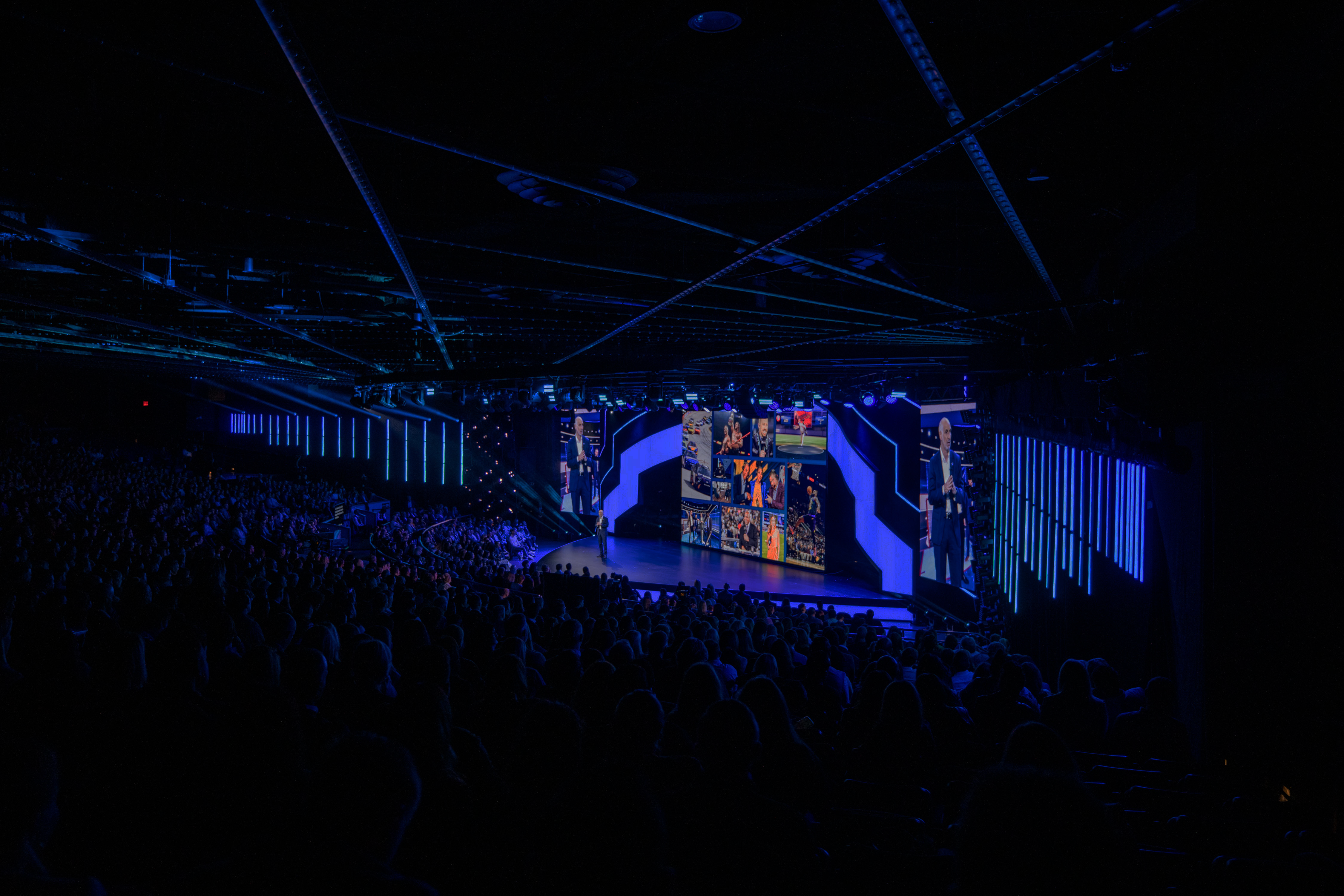 Person standing on stage with blue lights and LED wall