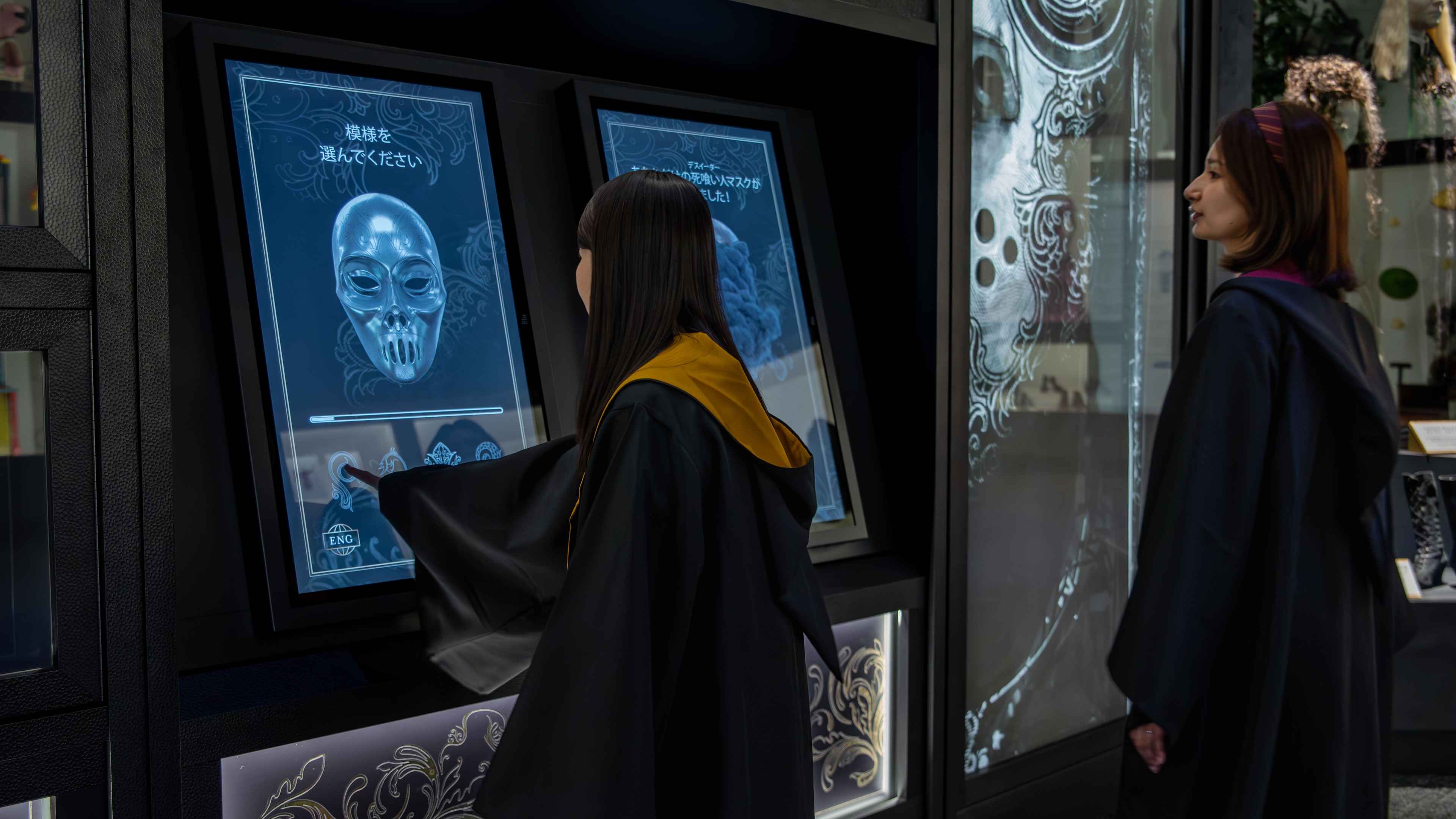 People in Wizards costumes engaging with interactive screen at Harry Potter experience