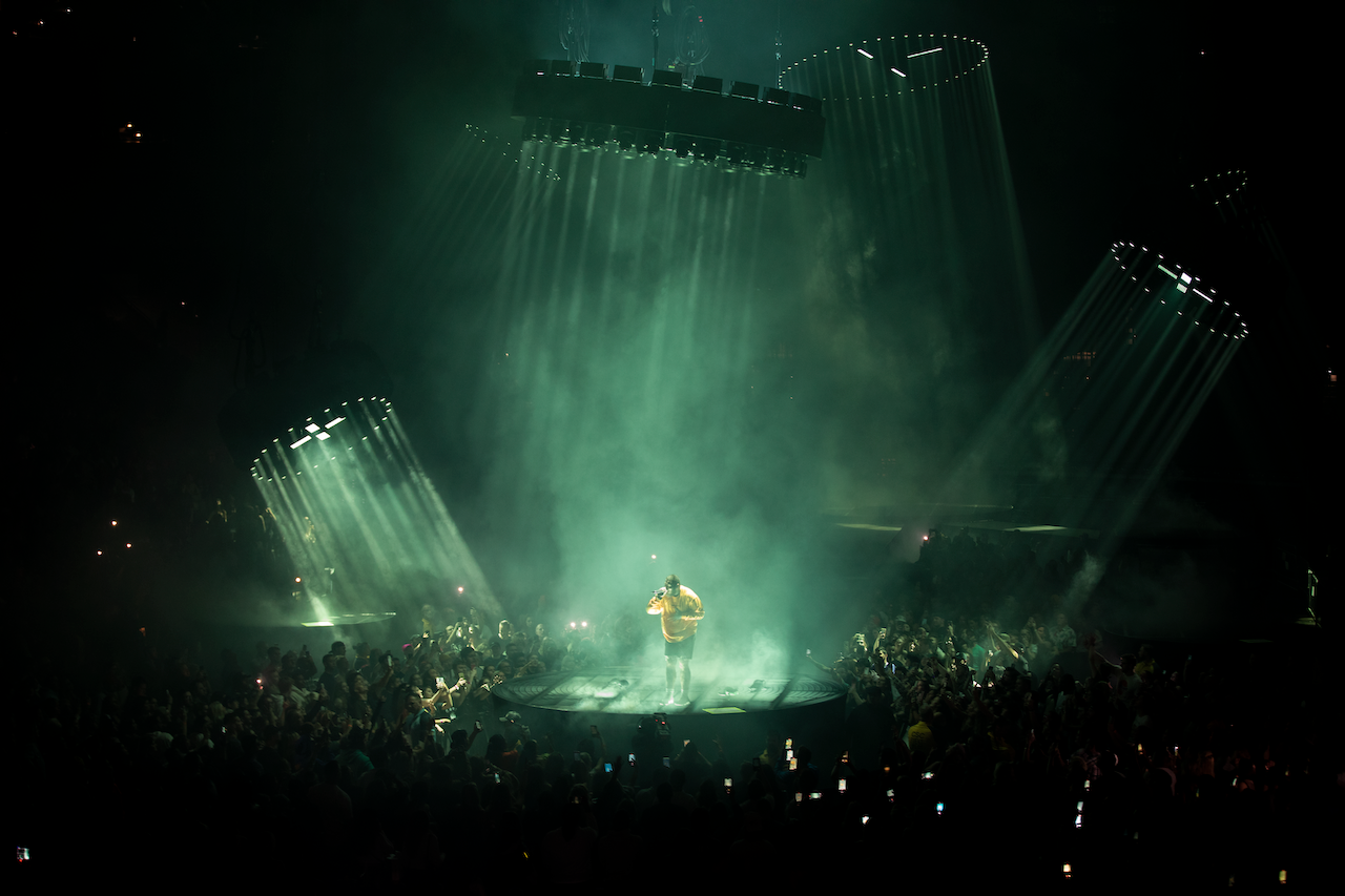 Post Malone in yellow shirt performing on green lit up stage