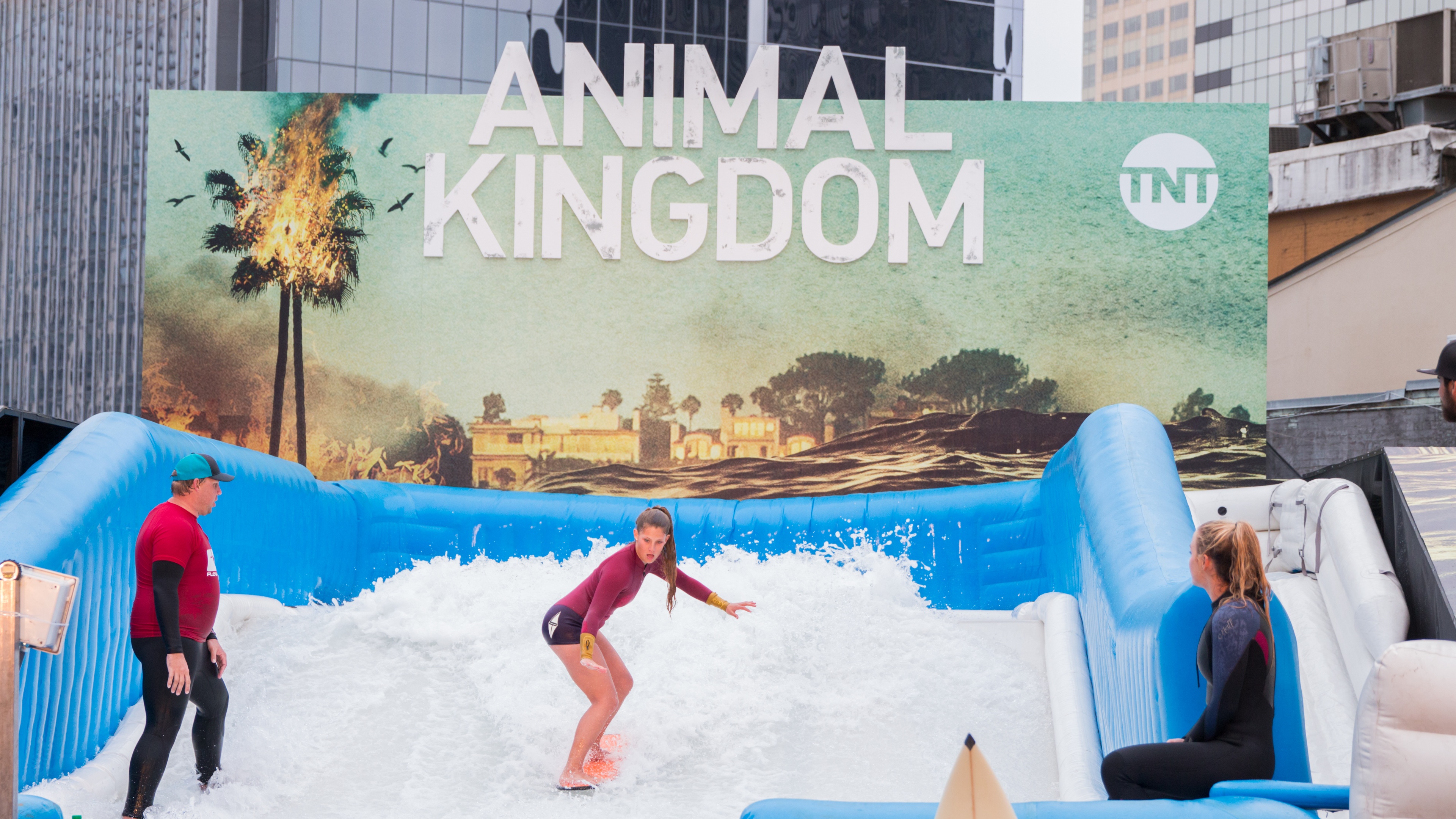 Woman on surfing simulator at brand activation with pop up backdrop in city