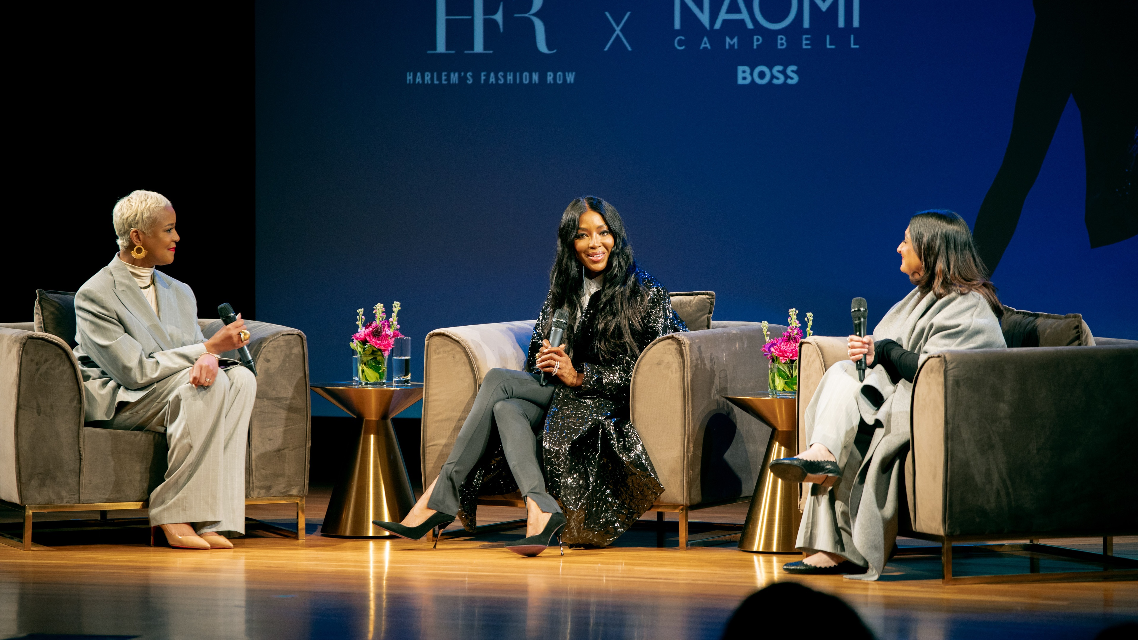 Naomi Campbell sitting on stage during event and smiling