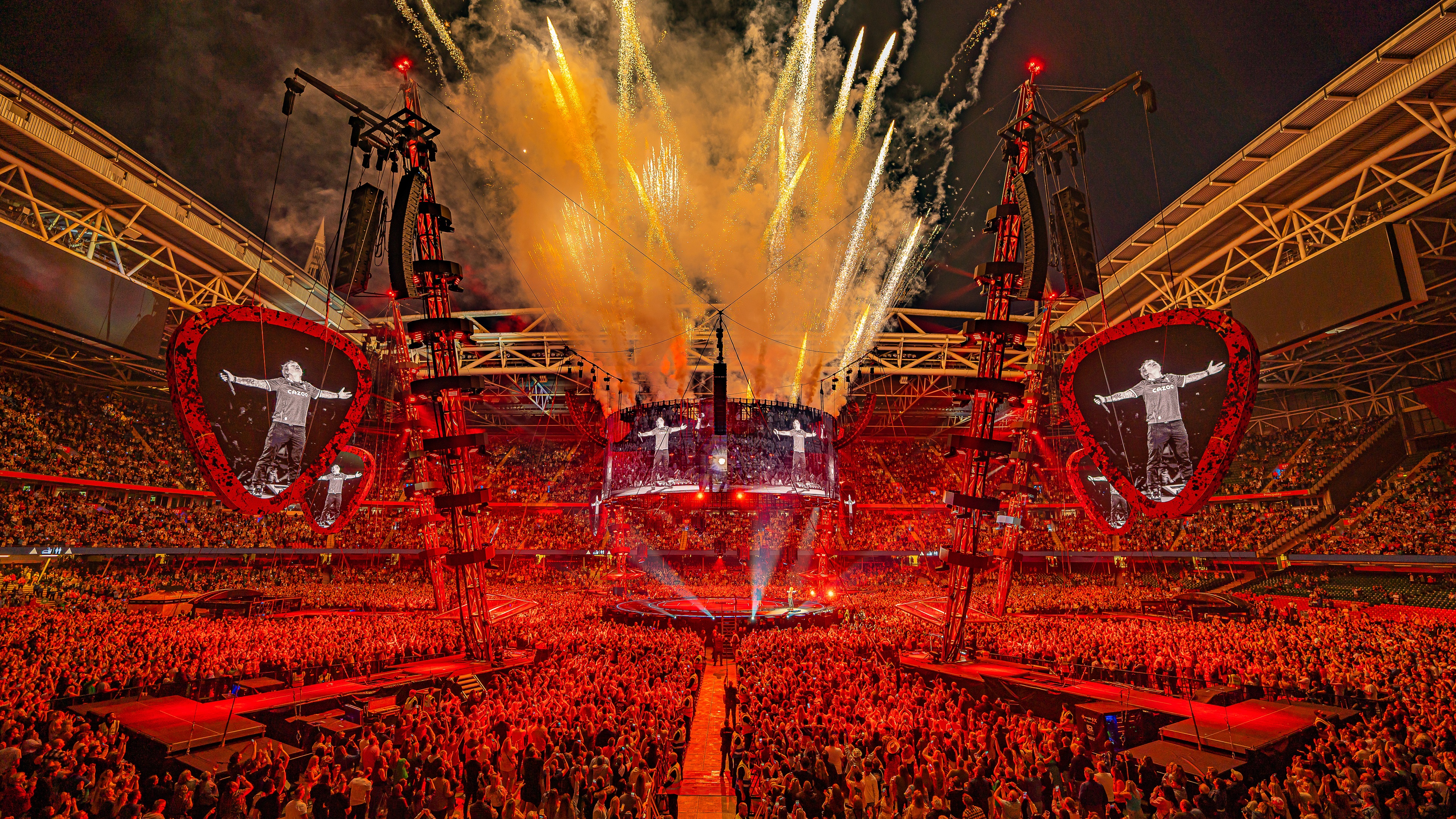 Ed Sheeran Mathematics stage lit up red with pyrotechnics coming out of top with large stadium crowd