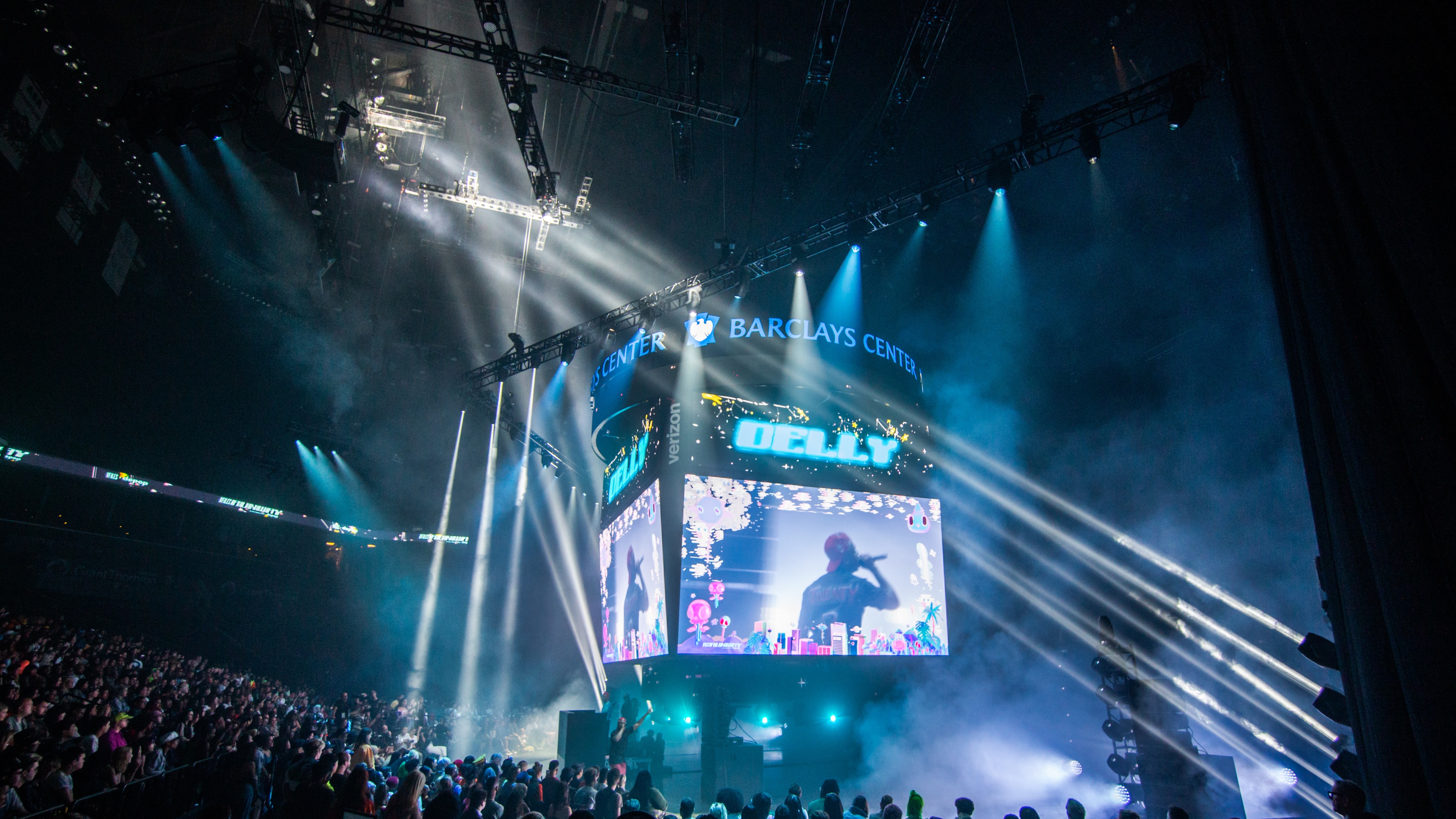 Large crowd with LED screen overhead showing performer