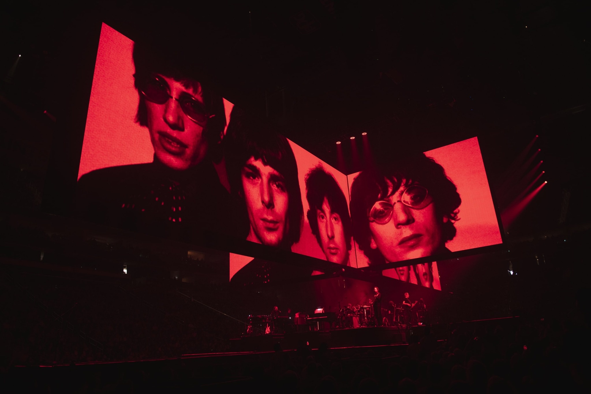 worm's eye view of Roger Waters performing during the This Is Not A Drill Tour, screen above the performers features a vintage photo of the band in duotone red
