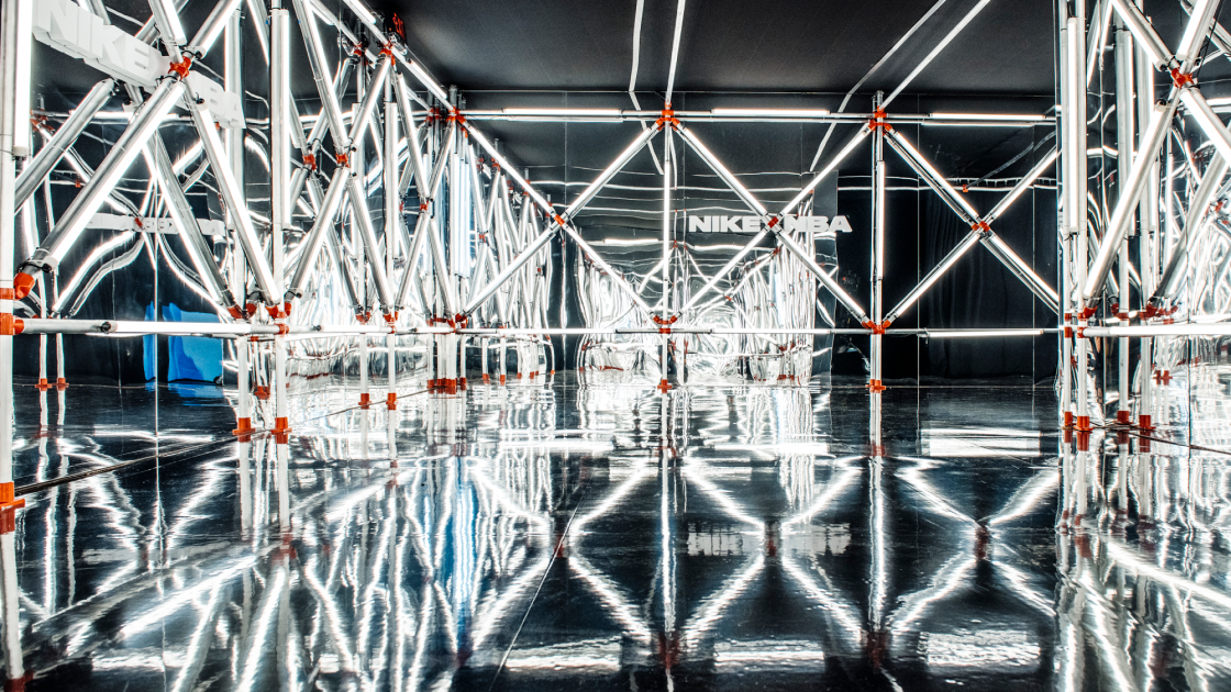 room-like structure created with white tube lights surrounded by mirrored floors and walls