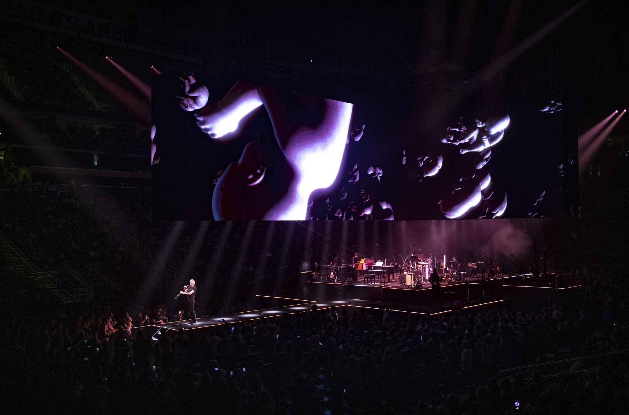 bird's eye view of Roger Waters performing during the Tand featurehis Is Not A Drill Tour, big screens above a pattern of babies in fetus position rolling in spacebab
