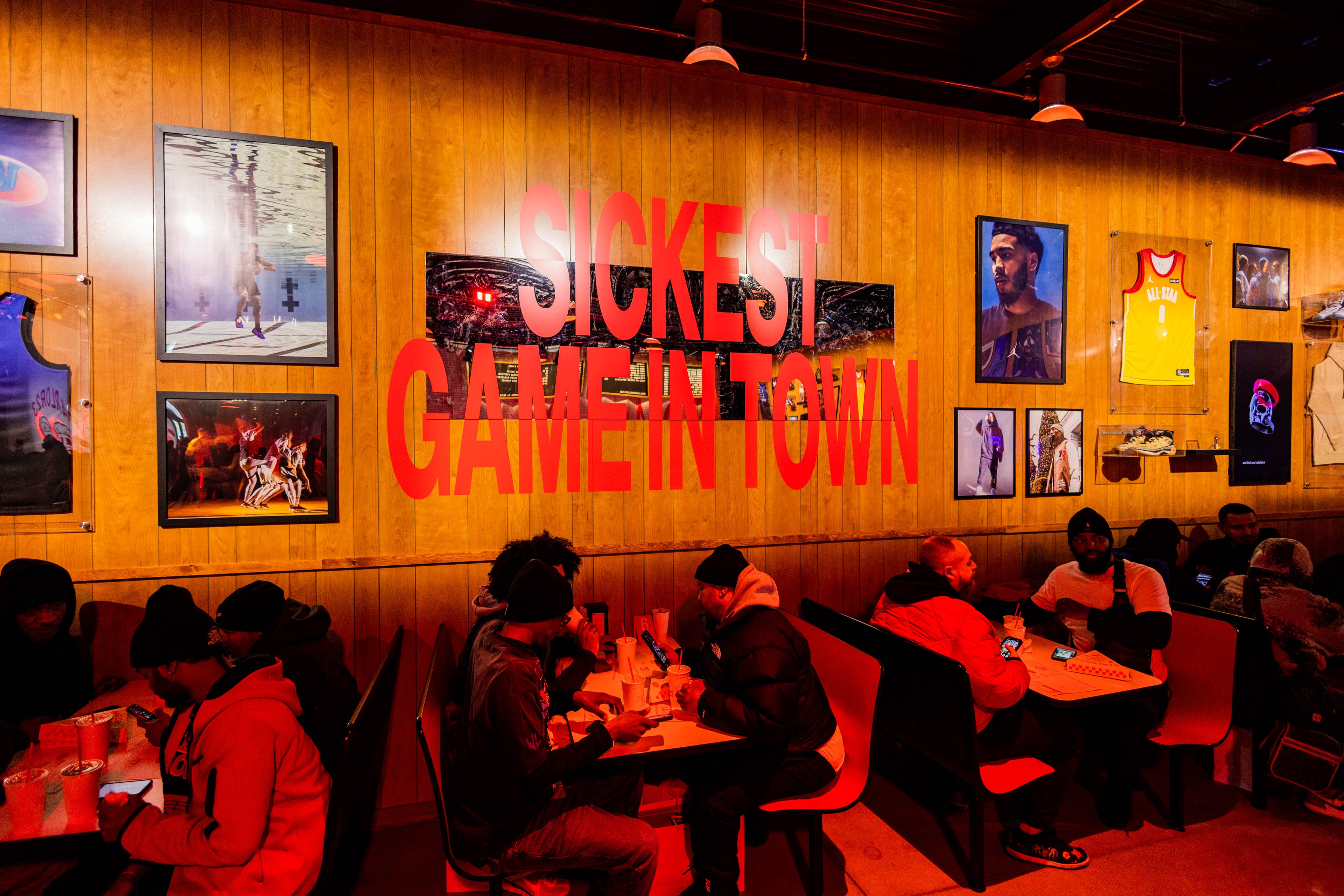 Jordan Parlor23 guests dining at booths with wooden wall behind them that says Sickest Game in Town