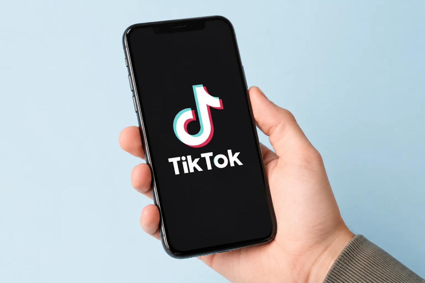 Hånd holder en mobil med TikTok-logoen på skjermen