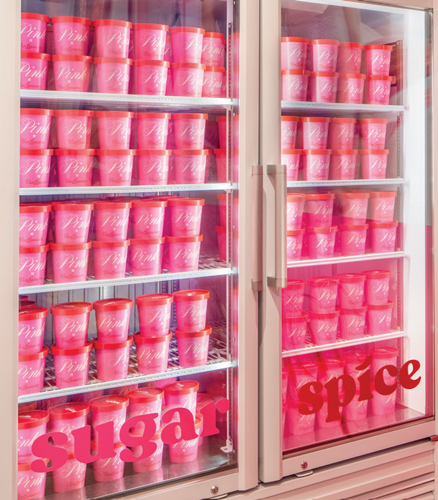 Store freezer filled with pink ice cream tubs under sugar and spice signage