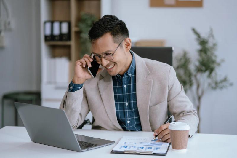 a man sitting at a desk talking on the phone