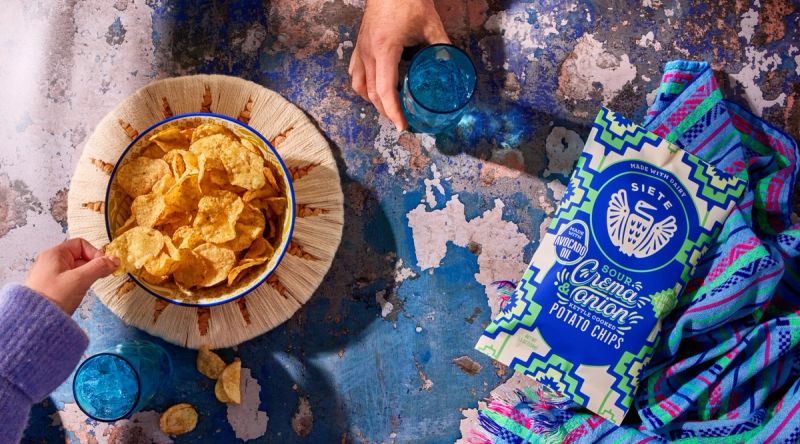 Sour Crema and onion chips in a bowl, with package and blanket laying next to 