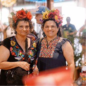 Two women wearing colorful floral headdresses.