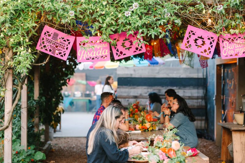 people eating at an asada with papel picado over their heads