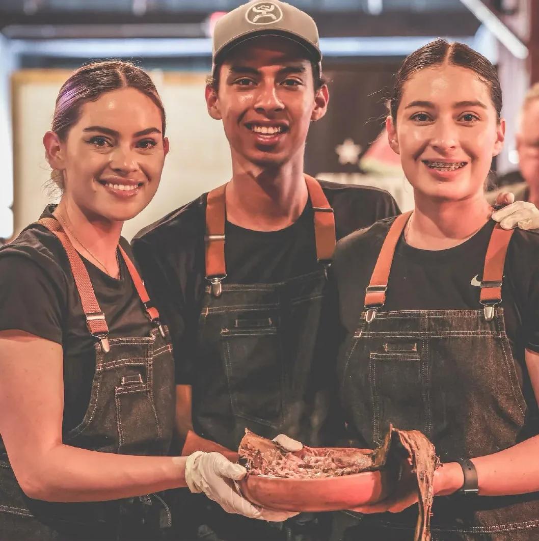 three people posing with taco dish 