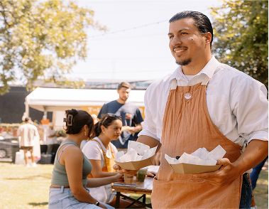 A man in an apron carrying food in paper plate boats.