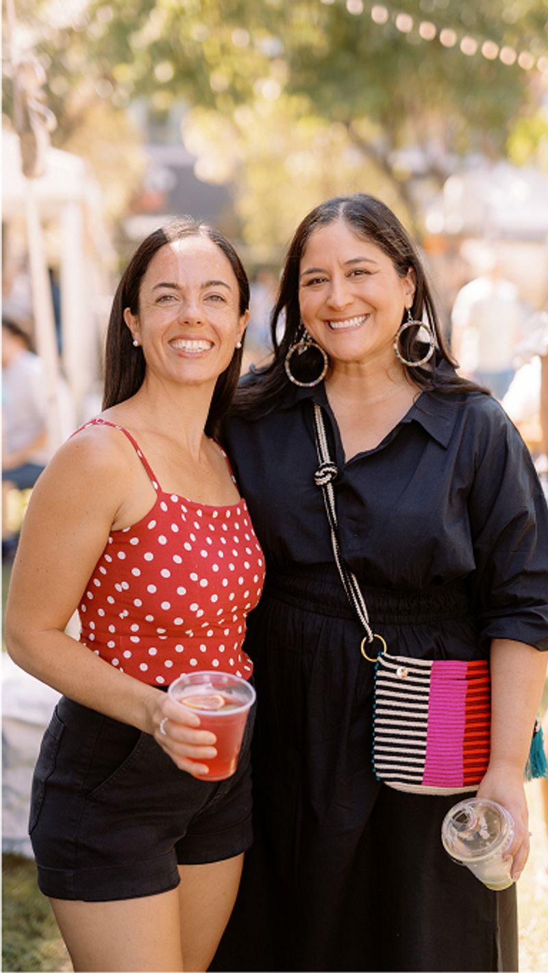 Two women standing site-by-side holding drinks.