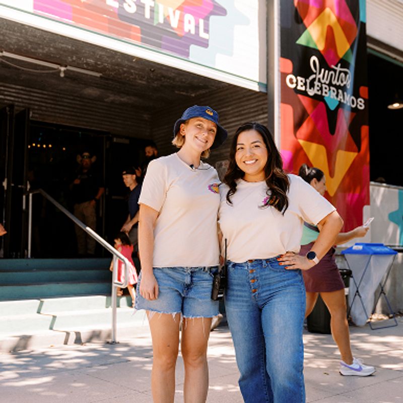 Two women standing in front of a Siete banner.
