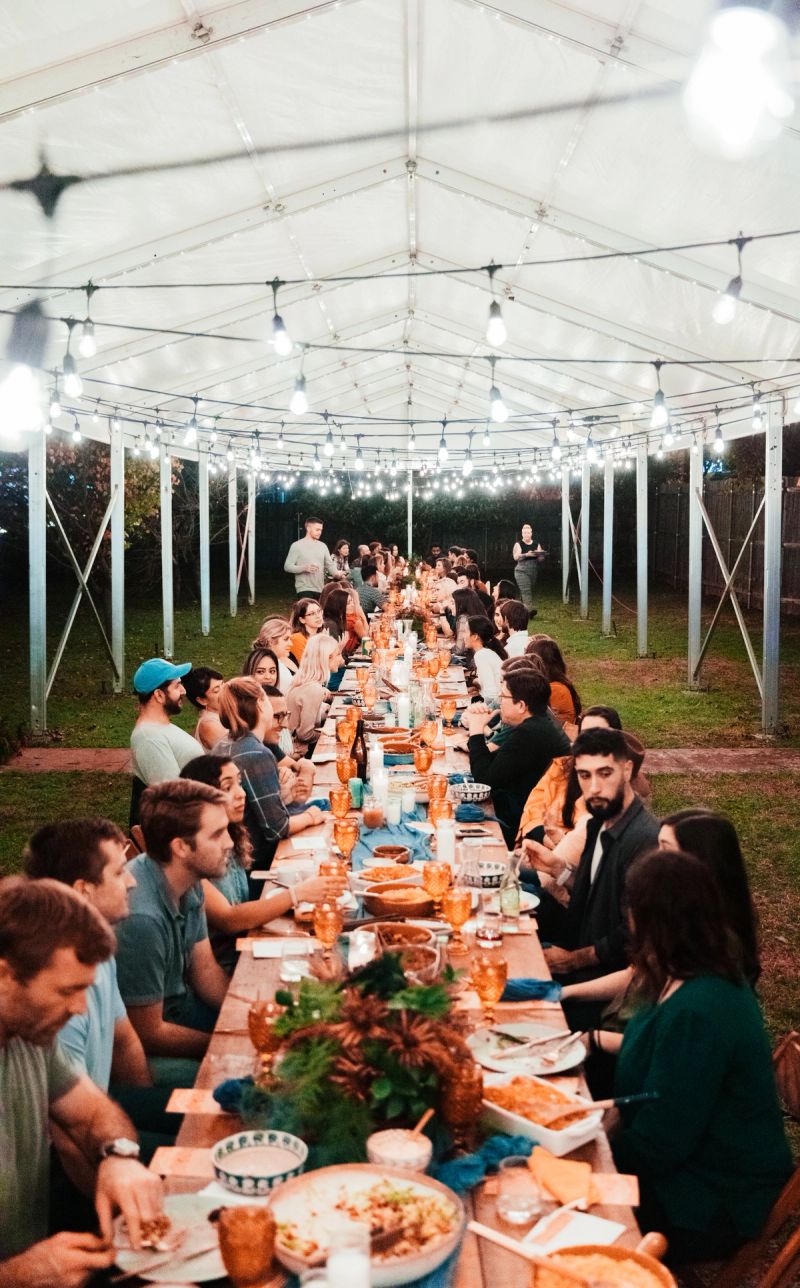 A large group of people dine together outside under a tent.