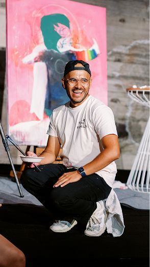 A painter kneeling beneath a mural.