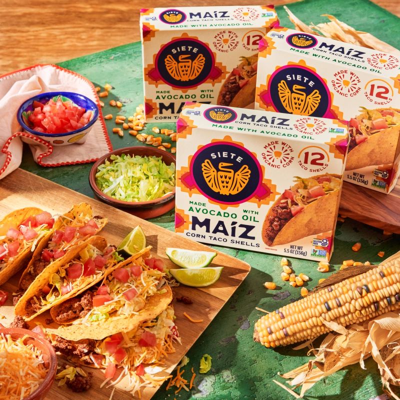 Maiz taco shells on table with tacos, corn husk, and salsa