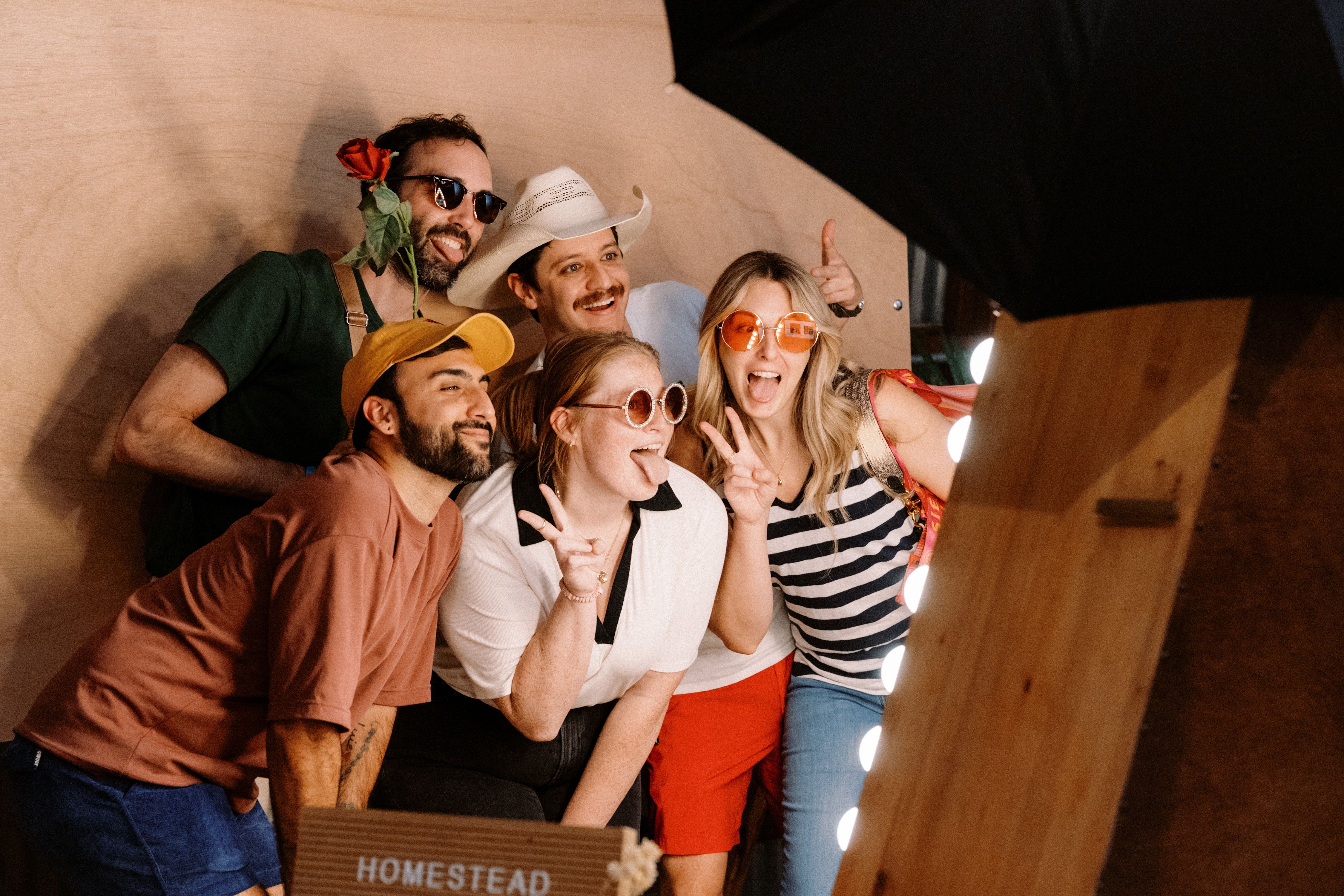 A group of people laugh together outside with drinks.
