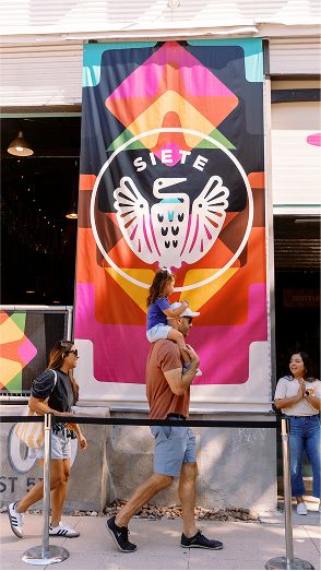 A family walking into the Juntos Festival beneath a Siete banner.