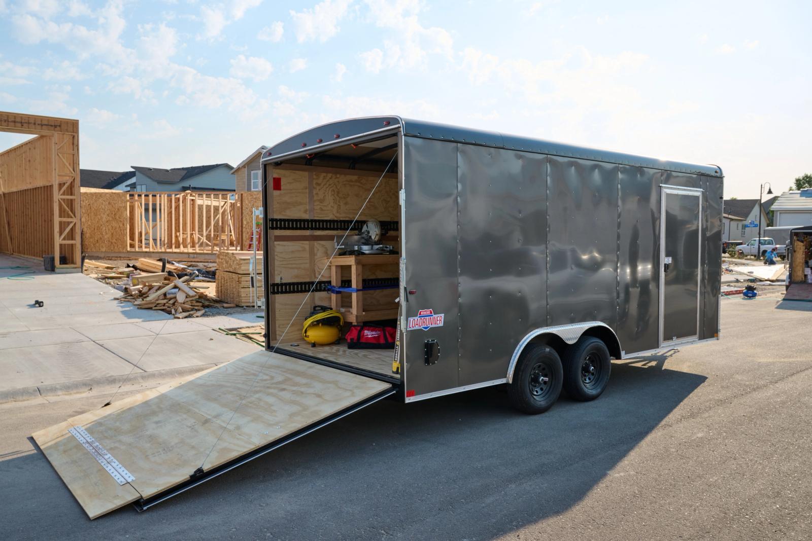 Rear view of a large gray enclosed cargo trailer with its ramp down. There is a sticker on the trailer with Loadrunner text.