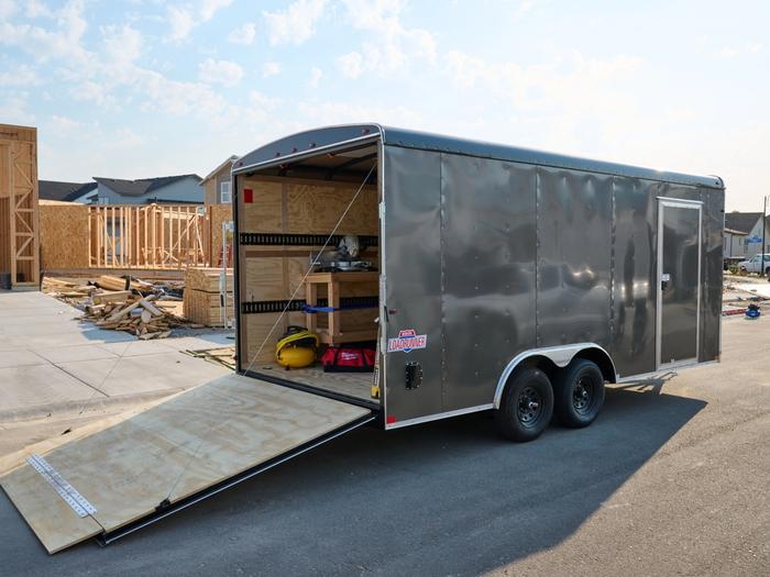 Rear view of a large gray enclosed cargo trailer with its ramp down. There is a sticker on the trailer with Loadrunner text.