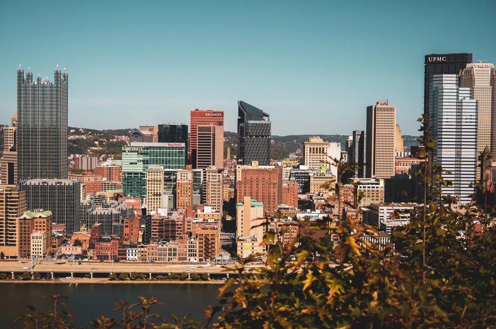 Horizontal view above the river in downtown Pittsburgh at sunset, with our new dealership location just north of the city