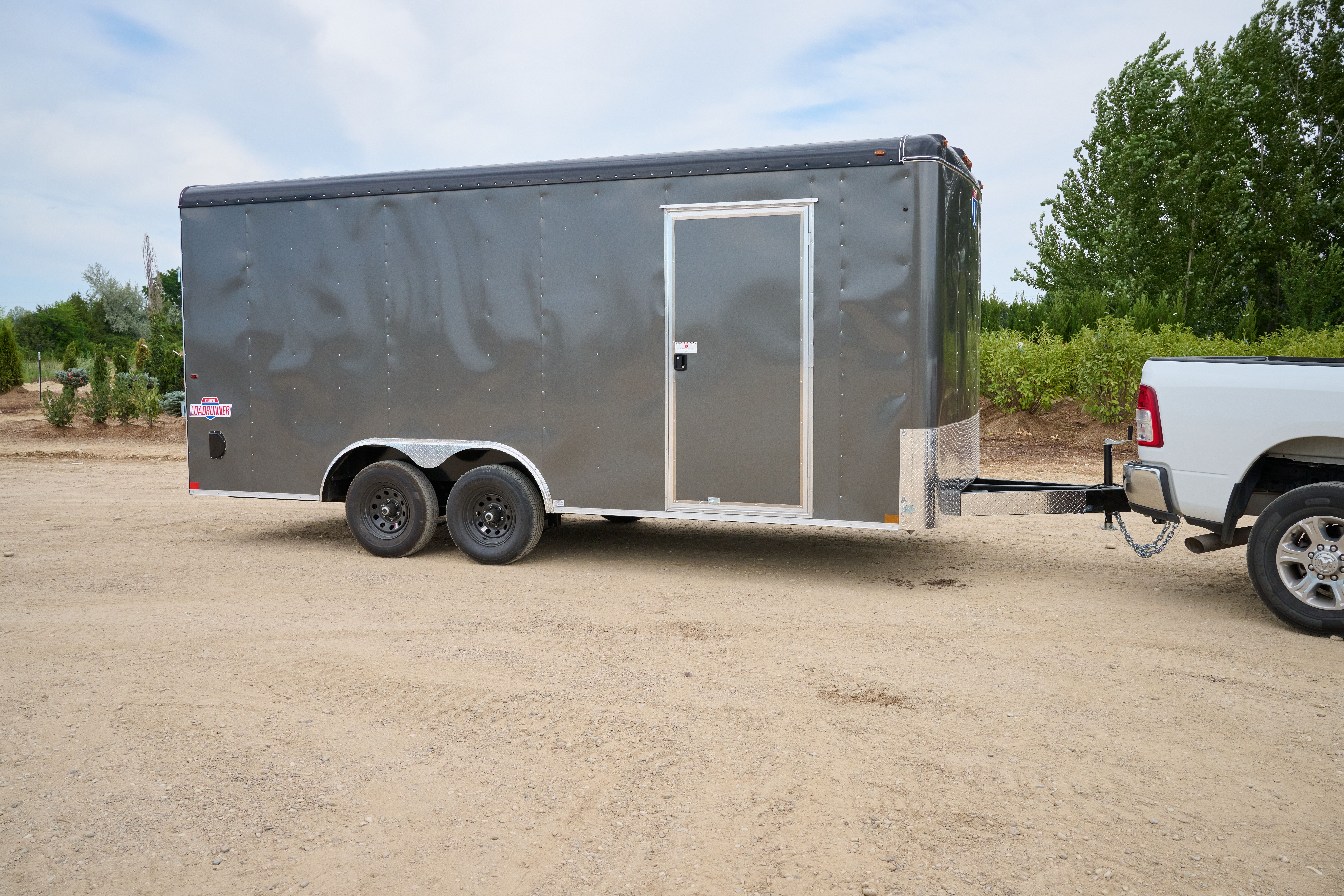 Gray cargo trailer with a side door attached to a white truck