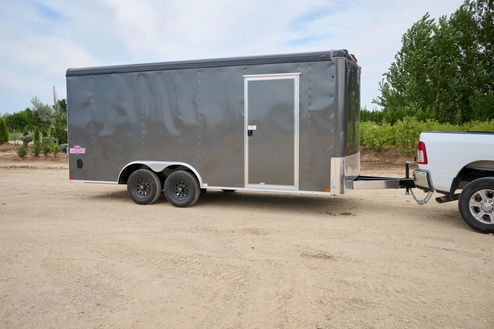 Gray cargo trailer with a side door attached to a white truck