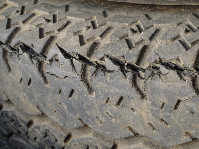 Close-up of a worn trailer tire tread with visible cracks and dry-rot damage along the rubber