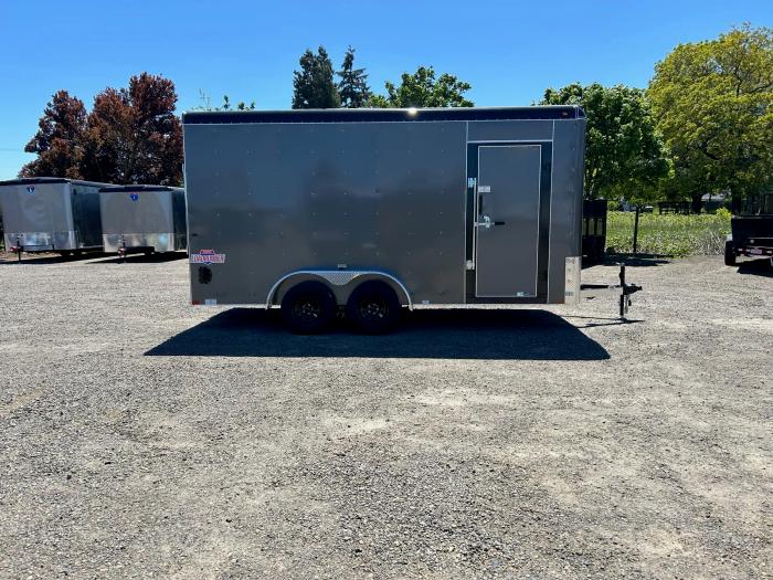 Charcoal-gray Interstate enclosed cargo trailer parked on a gravel lot with rows of white cargo trailers in the background
