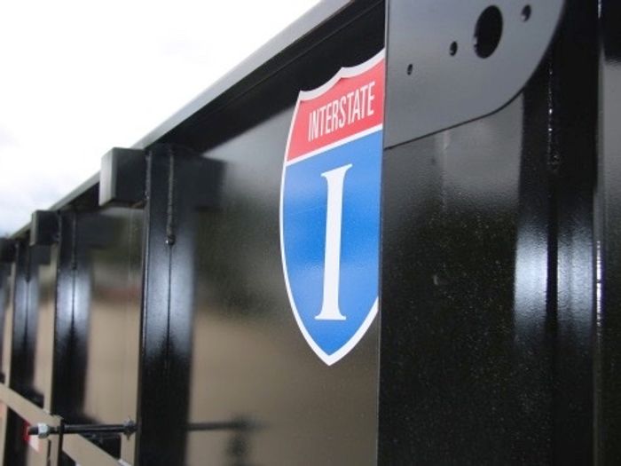 Close-up of a black trailer's side panel with a red, white, and blue Interstate I-shield decal