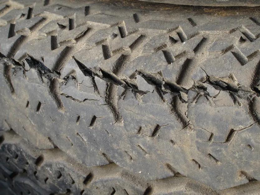 Close-up of a worn trailer tire tread with visible cracks and dry-rot damage along the rubber