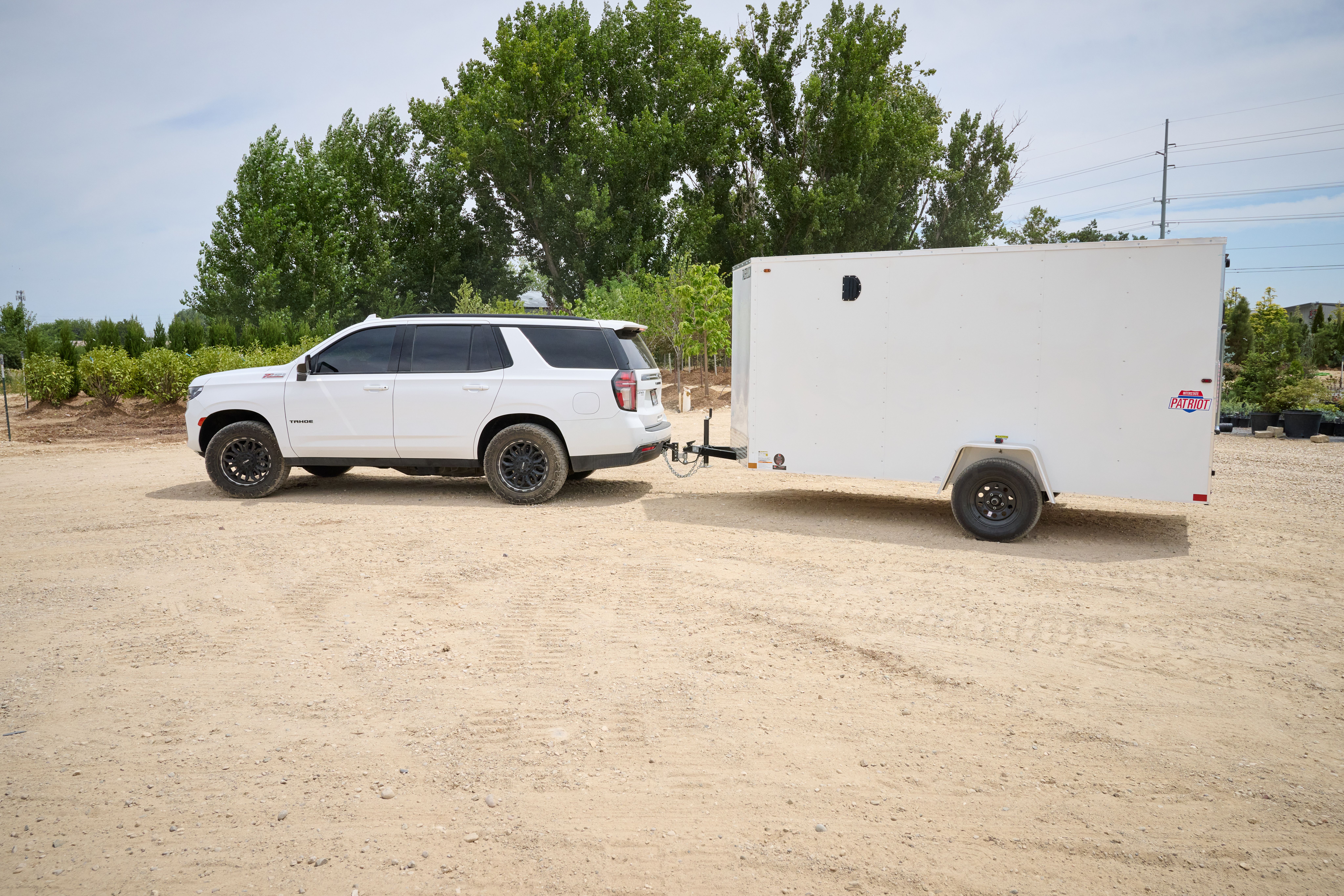 White Tahoe SUV towing a white 6x12 patriot cargo trailer