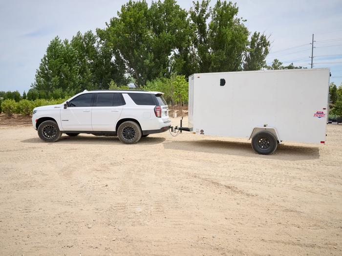 White Tahoe SUV towing a white 6x12 patriot cargo trailer