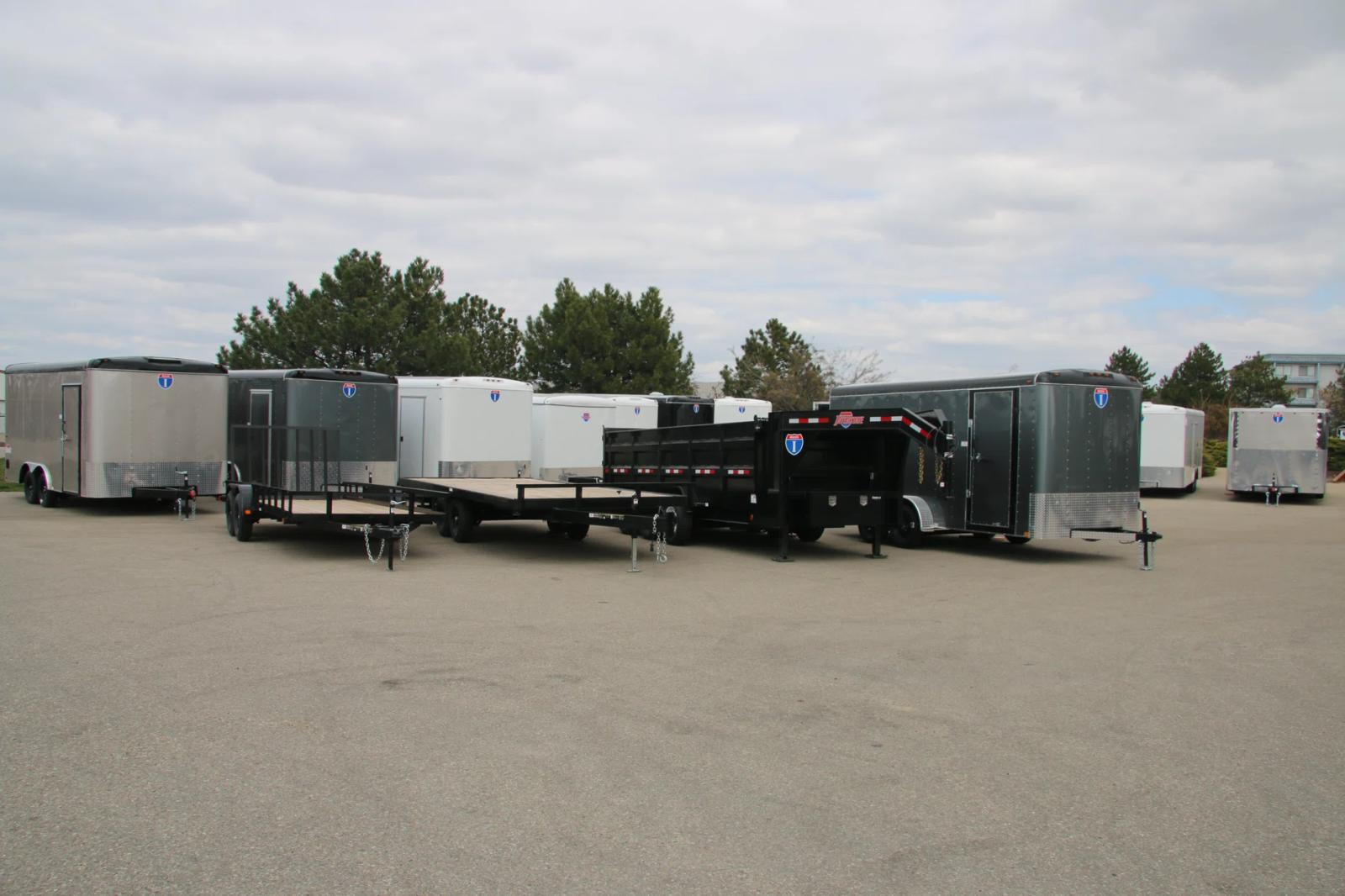 Lineup of a black utility, flatbed deckover, gooseneck dump, and charcoal enclosed cargo trailer with white cargo trailers behind on a TrailersPlus lot