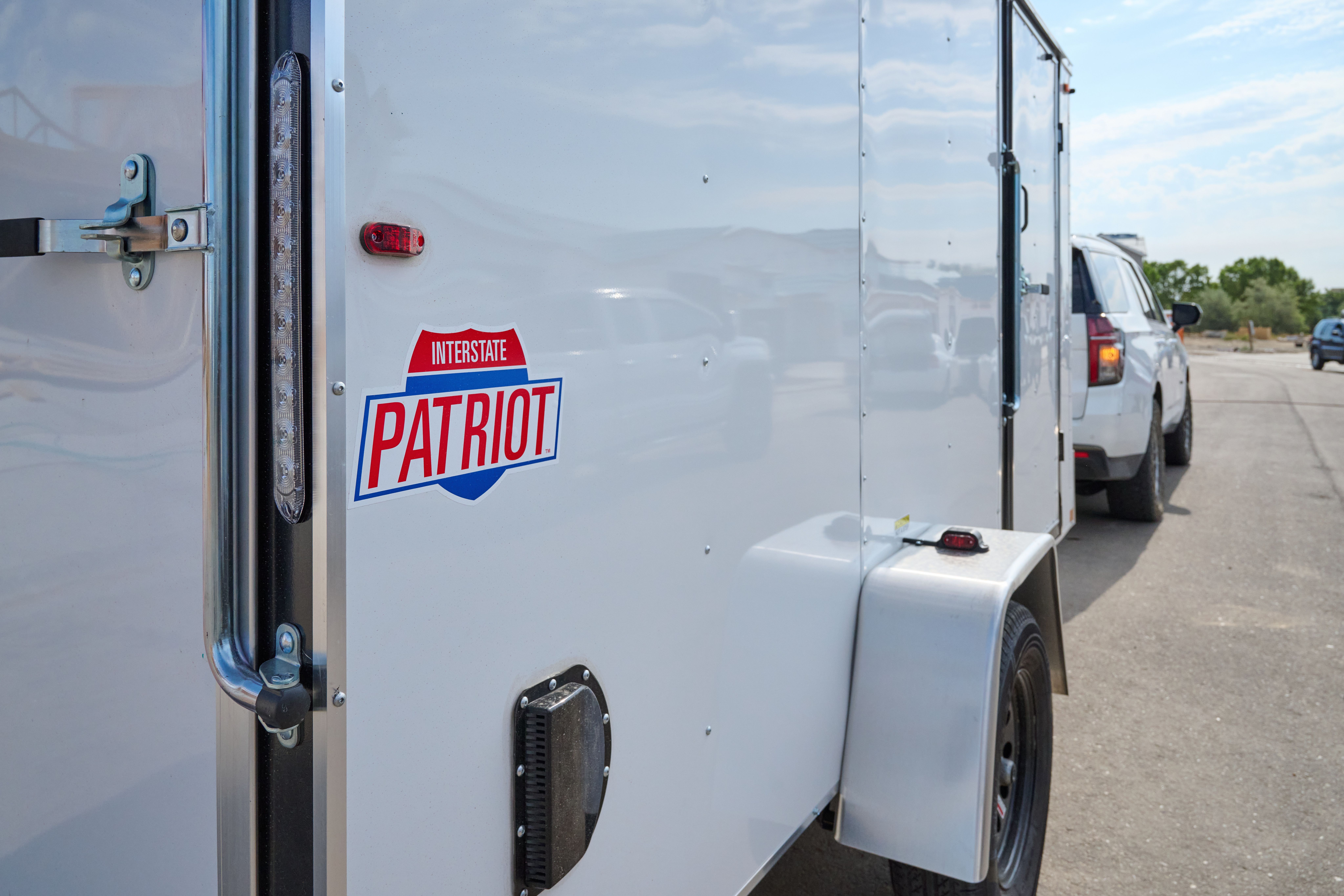 Rear panel view of a white cargo, trailer, focused on a sticker with text Interstate and Patriot