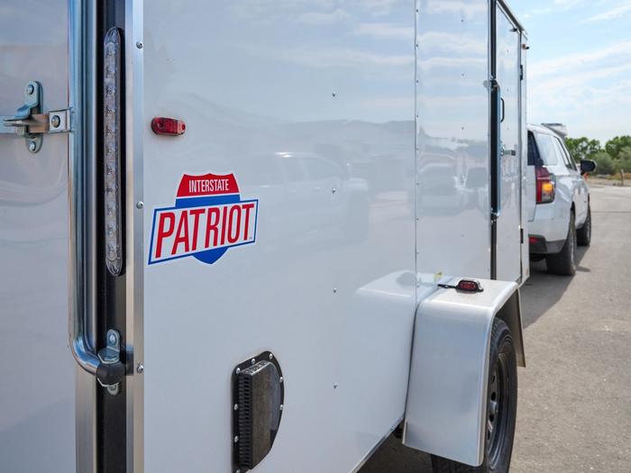 White Tahoe SUV towing a white 6x12 patriot cargo trailer