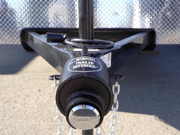 Close-up of a black trailer tongue with an Interstate Trailer Defender coupler lock and safety chains attached