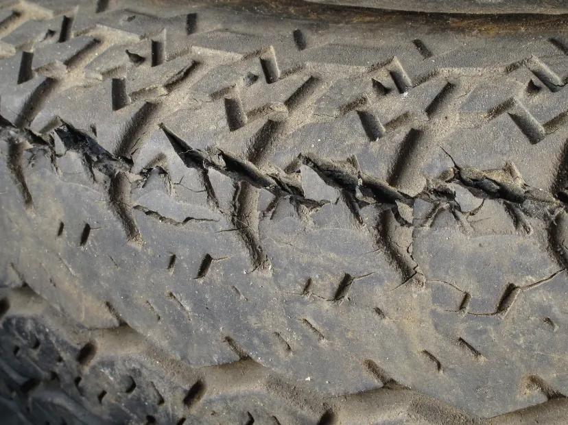 Close-up of a worn trailer tire tread with visible cracks and dry-rot damage along the rubber
