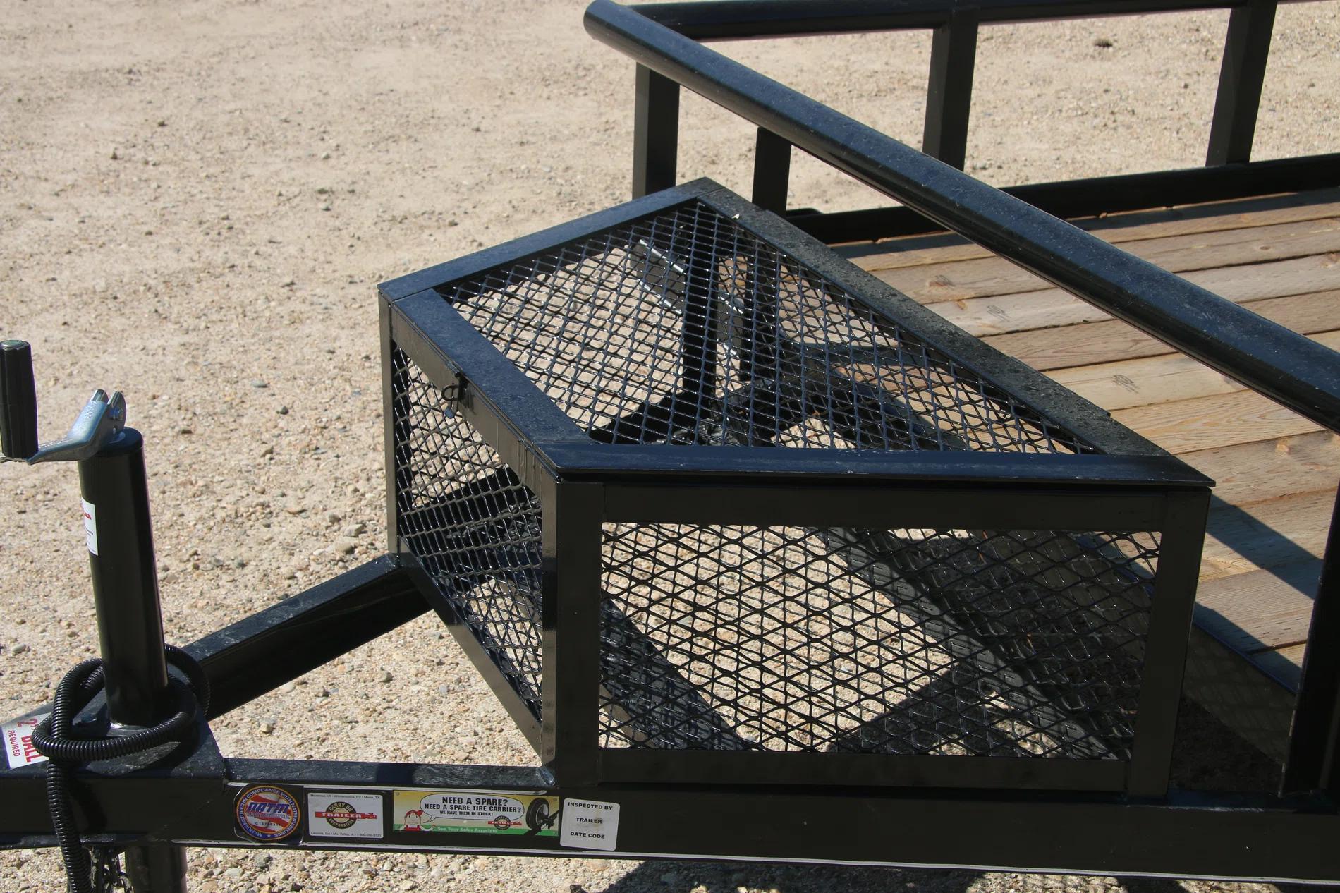 Close-up of a wire-mesh tongue storage box mounted to the front rail of a black utility trailer