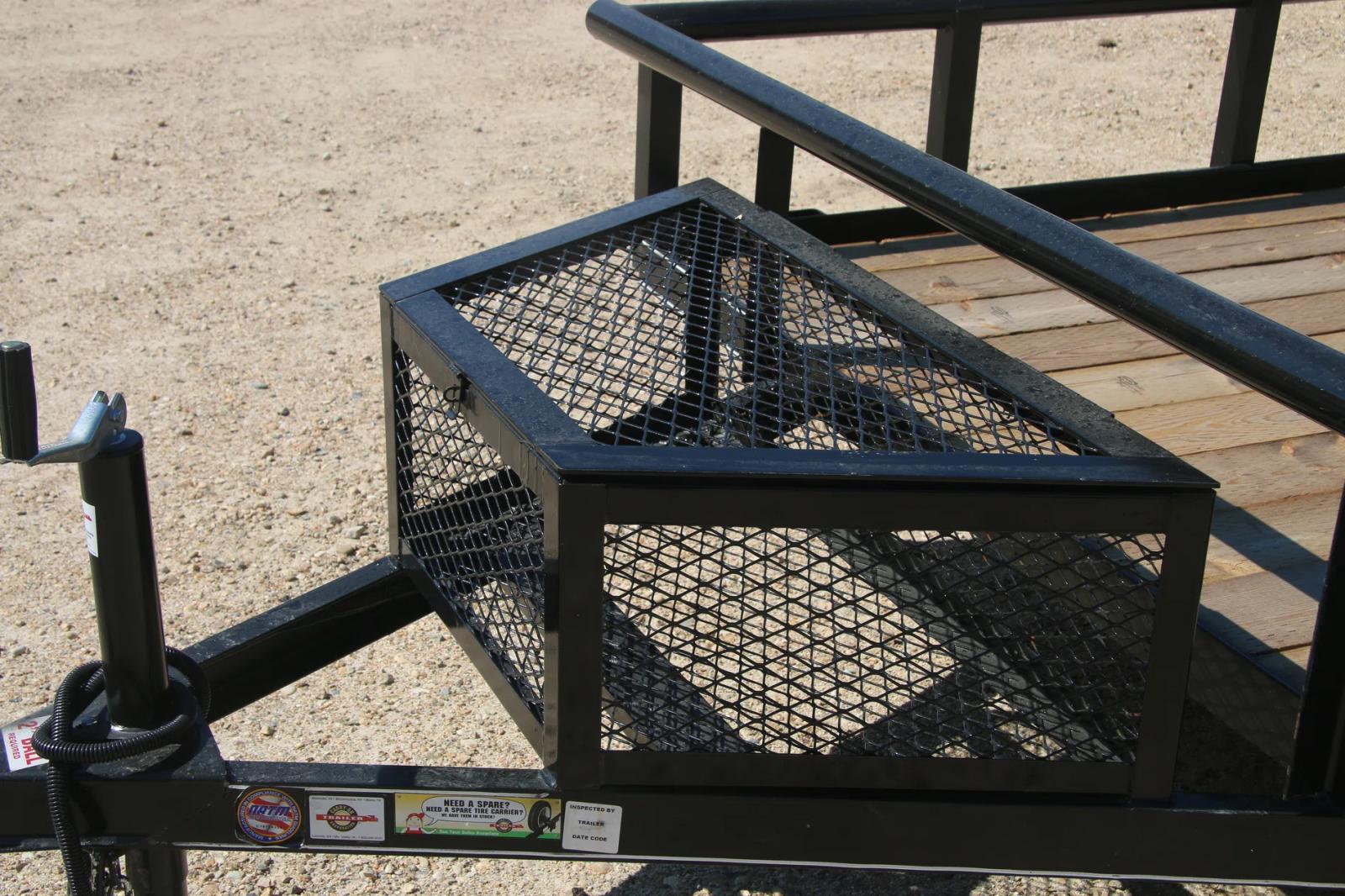 Close-up of a wire-mesh tongue storage box mounted to the front rail of a black utility trailer