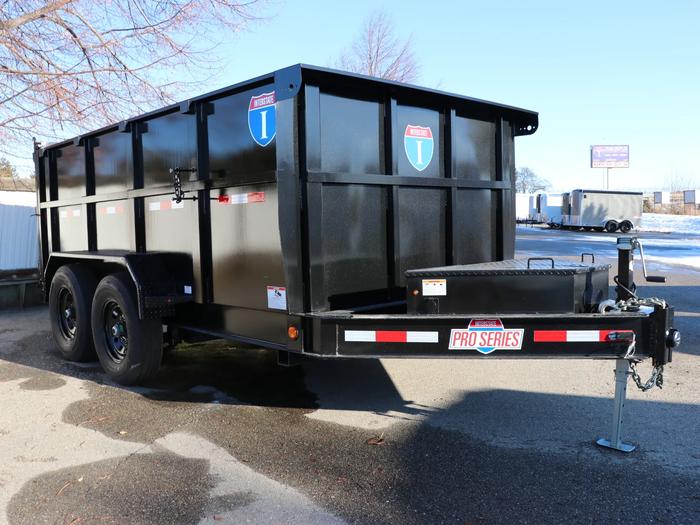Black tandem-axle dump trailer with tall walls and a 'Pro Series' badge parked on asphalt next to a snowy edge of a dealer lot