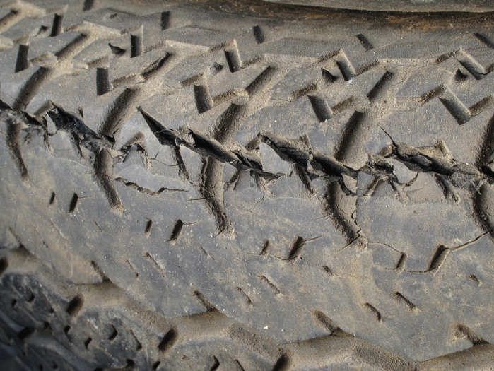 Close-up of a worn trailer tire tread with visible cracks and dry-rot damage along the rubber