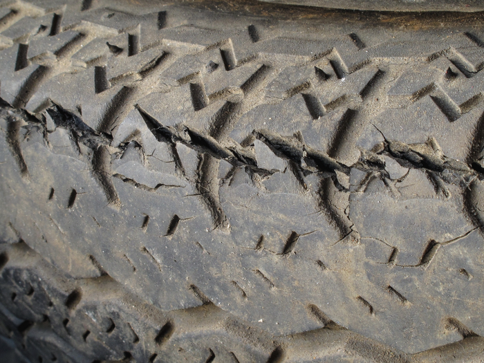 Close-up of a worn trailer tire tread with visible cracks and dry-rot damage along the rubber