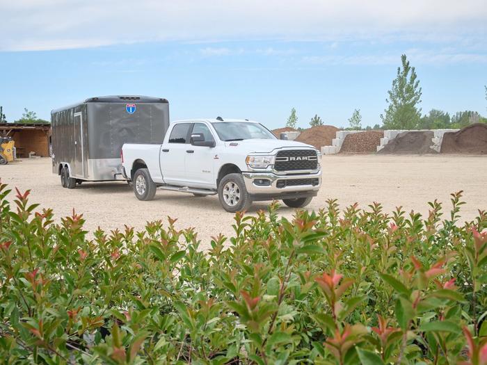 White truck towing a gray trailer, with landscaping material in the background